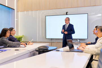 Businessman boss stand on the head of table lead the meeting and present agenda subject in meeting room for marketing plan, Co working space office.