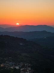 A sunset over a mountain range with a small town in the valley below Doi maesalong, Chiang rai,thailand