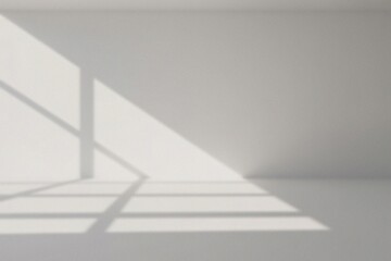 Obraz premium A sunlit room with window shadows, creating a minimalist and serene atmosphere. Shadows and light play across the wall and floor, giving a simple yet elegant visual