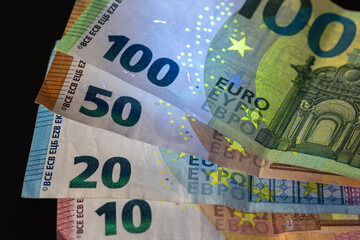 european euro banknotes under UV light, revealing advanced security features and anti-counterfeiting elements. financial banking and economy concept