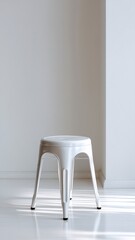 A white metal stool in perfect symmetry positioned in a bright, minimalist space with soft sunlight illuminating its form