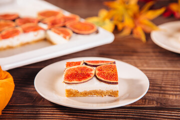 A delicious slice of fig and cream cheesecake on a white plate, topped with fresh fig slices
