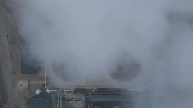 Aerial drone view of industrial turbine cooling fans, smoke plumes and vapour in foggy conditions, Bury Saint Edmunds, UK