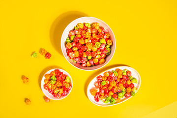Bowls of colorful cereal corn rings on yellow table. Breakfast concept.	