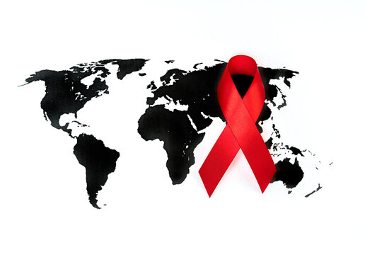 Red ribbon aids awareness symbol over world map