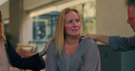 Crying woman comforted by group members during emotional moment in therapy session, expressing pain while receiving compassionate support and presence