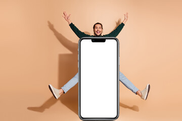 Energetic man posing behind blank board against beige background, showcasing casual style and excitement
