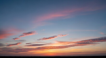 Stunning sunset with vibrant orange and pink clouds over a silhouetted horizon. The sky transitions from deep blue to warm hues, creating a breathtaking natural display.