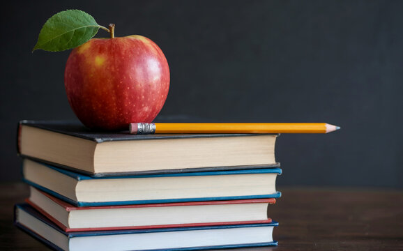 Red Apple and Yellow Pencil on Stack of Books against Blackboard Background