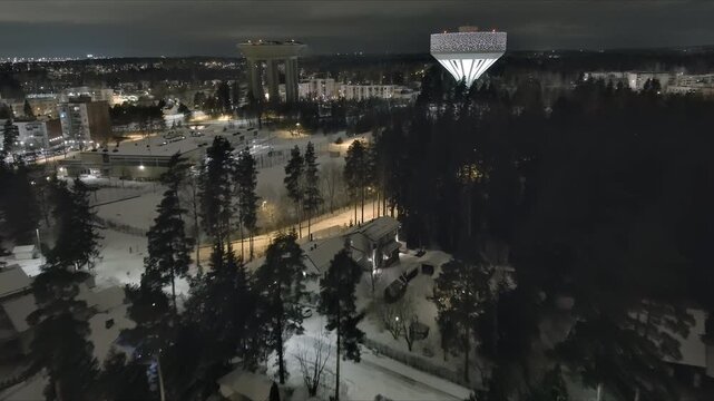 Vantaa.Finland-December 29.2021: High angle view of the new water tower beside the old one in Hiekkaharju Vantaa. Pretty cityscape. Nighttime. Wintertime. Drone slowly moving forward.