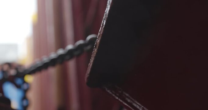 Massive truck locked within steel cargo bay. Chains shimmer under dim light as waves echo nearby. Heavy vehicle secured tight in ship hold