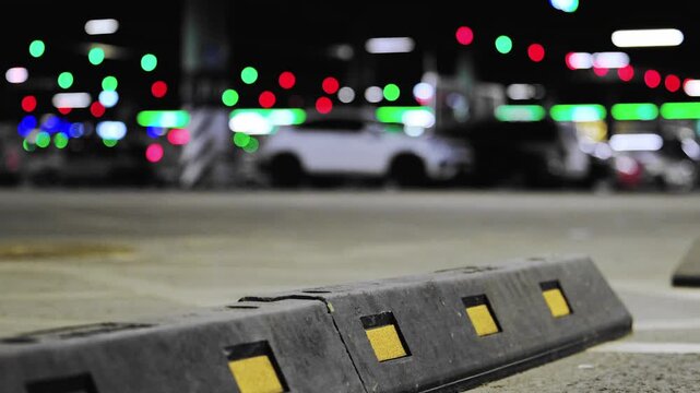 Background, blur, out of focus, bokeh. Bright reflectors on concrete, Nighttime parking area with glowing signals, Closeup of urban concrete surface featuring yellow reflectors and blurred vehicle