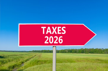 Taxes 2026 new year symbol. Concept words Taxes 2026 on beautiful red road sign. Beautiful green grass field forest and blue sky background. Business and taxes 2026 new year concept. Copy space.