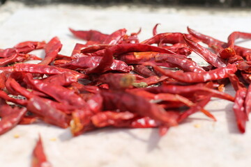 Dried red chili peppers on a white surface, ready for cooking