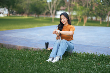 Woman checking smartwatch while relaxing in park