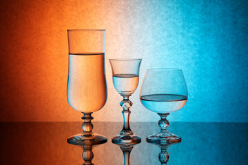 Three glass goblets on a colored gradient background