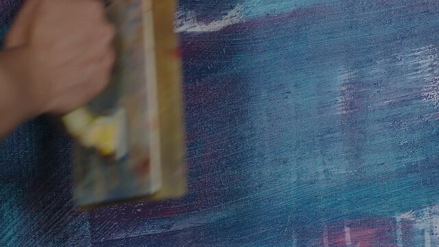 Leichte Spachtelbewegungen auf bemalter Leinwand &ndash; verwischte Acrylfarbe, dynamische Texturen und kreativer Malprozess im Kunststudio