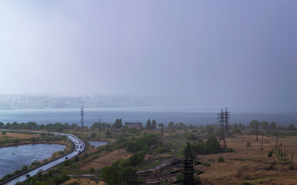 Rainstorm over lake and industrial cityscape