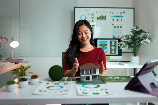 Woman architect analyzing eco-friendly house model for sustainable design