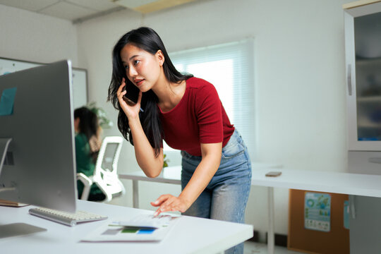 Woman multitasking working in office making phone call