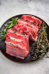 Raw Beef Kalbi Short Ribs, fresh meat with bone on plate with thyme. grey background. top view