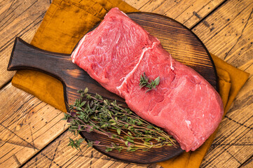 Fresh raw bison meat displayed on a wooden board, showcasing its rich red color and tenderness, ideal for gourmet cooking adventures. wooden background. top view © Mironov