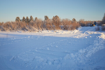The road is an ice crossing over a river in the snow in winter.