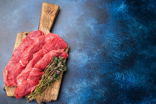 Beautifully sliced raw buffalo meat on a rustic platter, showcasing its appealing color and quality, perfect for grilling or roasting. blue background. top view