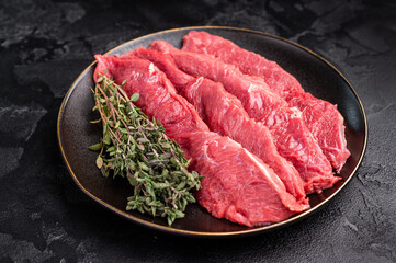 Raw sliced horse meat steaks presented with herbs and spices, inviting creativity in the kitchen for those seeking bold flavors and unique dining experiences. black background. top view