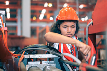 Professional Black African female factory engineer/worker/technician operate machinery in modern industrial plant. She wear safety helmet,vest show focus,skill in repair maintenance production process