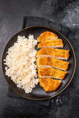 Delicious katsu style dish, featuring a perfectly cooked chicken meat cutlet served alongside steamed rice for a balanced meal. black background. top view
