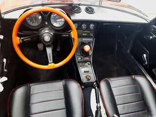 Interior panel of an old car, seats and steering wheel in wood.