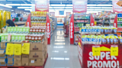 Obraz premium Blurred background of interior of supermarket store aisle with various products on shelves and a prominent 