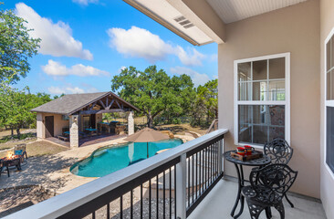 A balcony with a table and chairs overlooking a beautiful pool