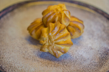 view of four star-shaped choux pastry cream puffs or profiteroles arranged on a rustic ceramic plate concept of dessert, baking, european patisserie, sweet treats