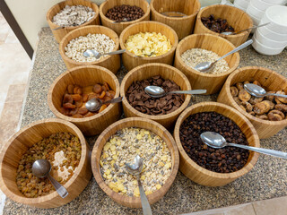 Breakfast buffet with a rich assortment of cereals, muesli, and dried fruits in wooden bowls. Healthy self-service breakfast bar at a hotel.
