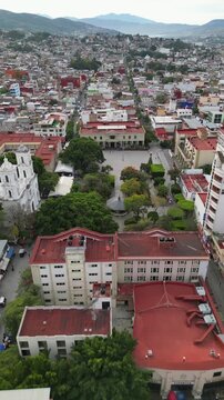 Forward vertical drone shot flying over Chilpancingo's central plaza with holiday ornaments and trees