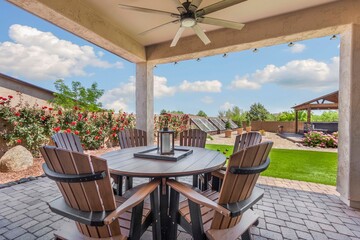 An outdoor patio with a table and chairs under a ceiling fan