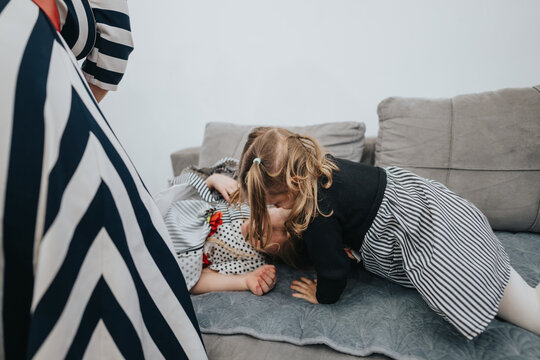Two young children share a joyful moment playing together on a comfortable sofa. The scene radiates warmth and family harmony within a cozy home environment.