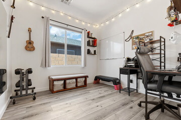 A cozy home office with a stylish desk, chair, bookshelf, and fan