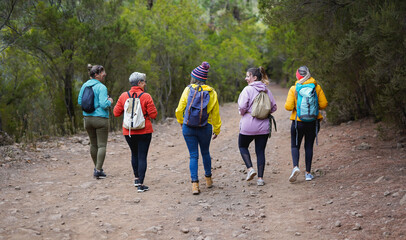 Back view of multi generaitonal women hiking together during fall season - Sport, active lifestyle and multiracial people