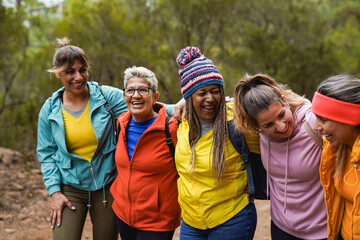 Happy gorup of multiracial women hugging each other during trekking day in nature - Multi generational people, hiking and friendship concept