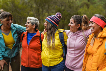 Happy multiracial women hugging each other during trekking day outdoor - Multi generational group of people, hiking and fall season concept