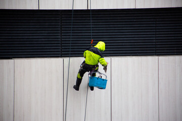 Industrial climber at height searches for tool in his equipment box. This dangerous profession is...