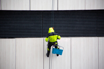 Close up photo of industrial climber at height. The process of hard labor in dangerous, life...