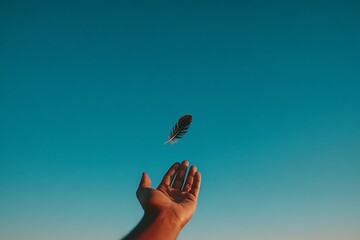 An open hand reaching up as a single feather floats down against a deep blue, gradient sky. Symbolizes freedom, lightness, letting go, spirituality, and mental clarity.