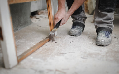 A young man pulls out nails with a crowbar.