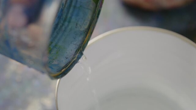 Nahaufnahme von Wasser, das aus einem Beh&auml;lter in einen Eimer gegossen wird &ndash; detailreiche Fl&uuml;ssigkeitsbewegung in kreativer Studio- oder Werkstattszene