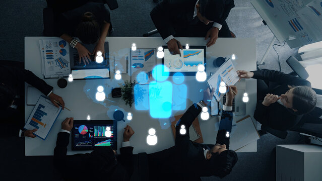 A diverse team of professionals collaborates in a modern conference room, using technology and data visualizations to enhance strategic planning and foster innovation. Trope - Powered by Adobe