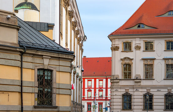 Historic Wrocław architecture with Baroque façades and red roofs framing the distinctive red-white building visible prominently in background